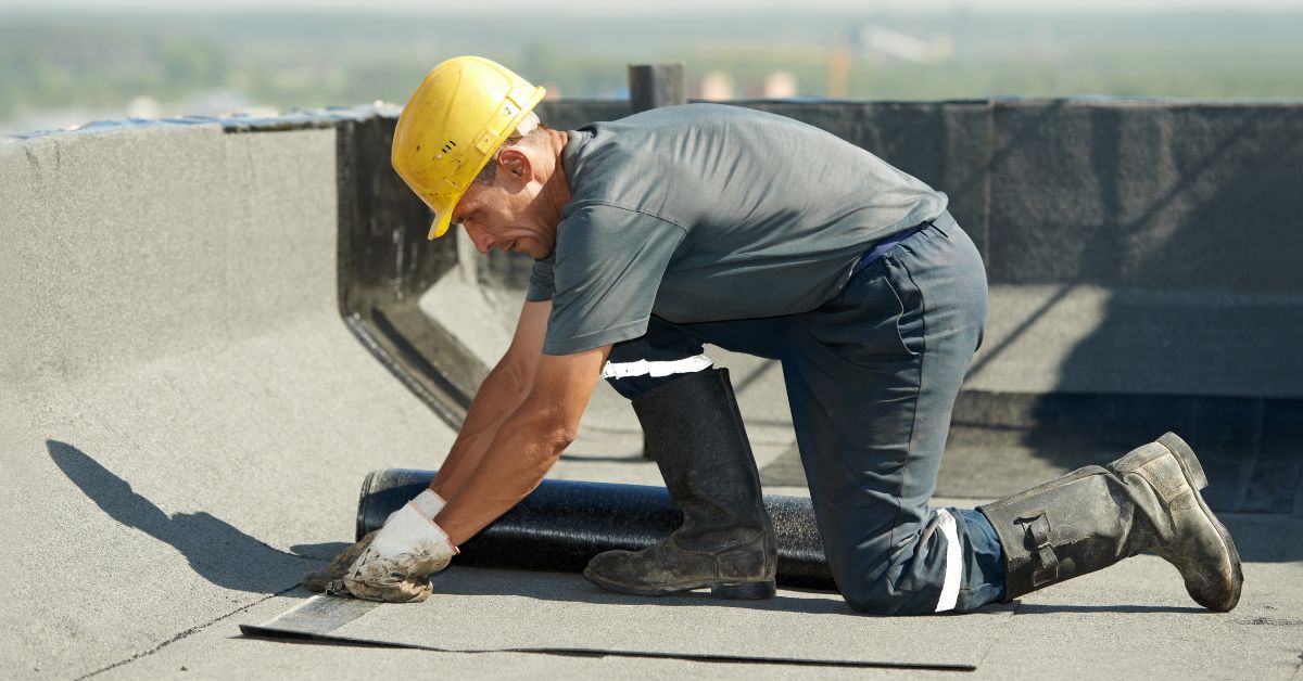 a roofer working on a flat roof waterproofing project